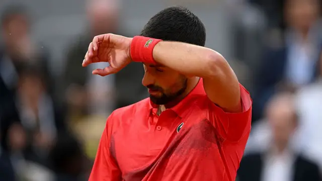 Novak Djokovic wipes his face