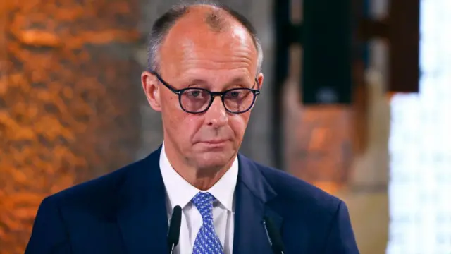 Merz stands at a lectern