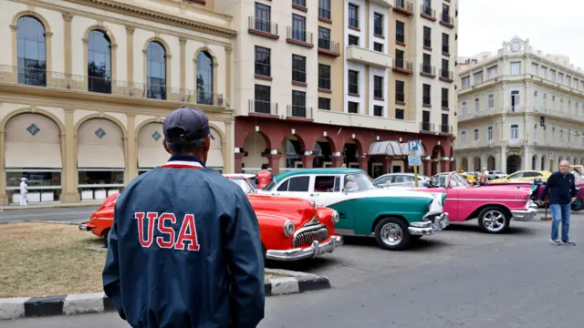 A man wearing a jacket with the words 'USA' in a street in Havana, Cuba