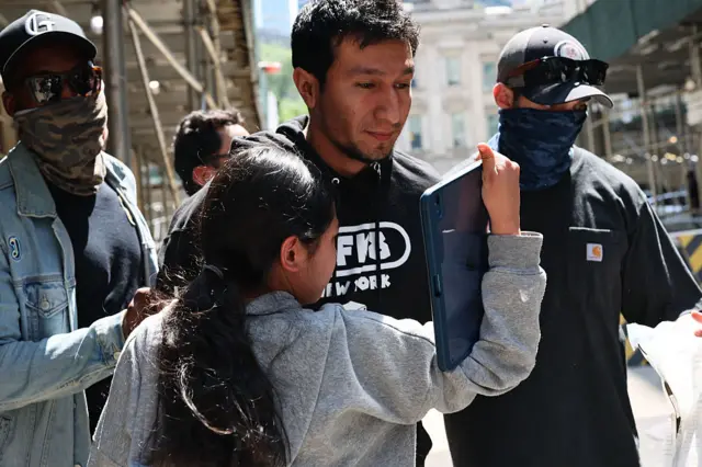 child attempts to embrace her father as he is escorted by federal agents with other detainees to vehicles after exiting an Intensive Supervision Appearance Program office
