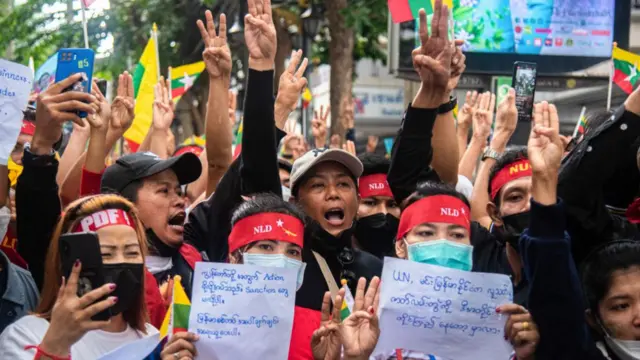Pro-democracy Burmese protesters make the three-finger salute while demonstrating outside the Burmese embassy in Bangkok