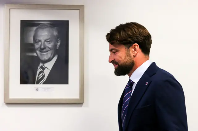 Russell Martin walking by picture of Walter Smith