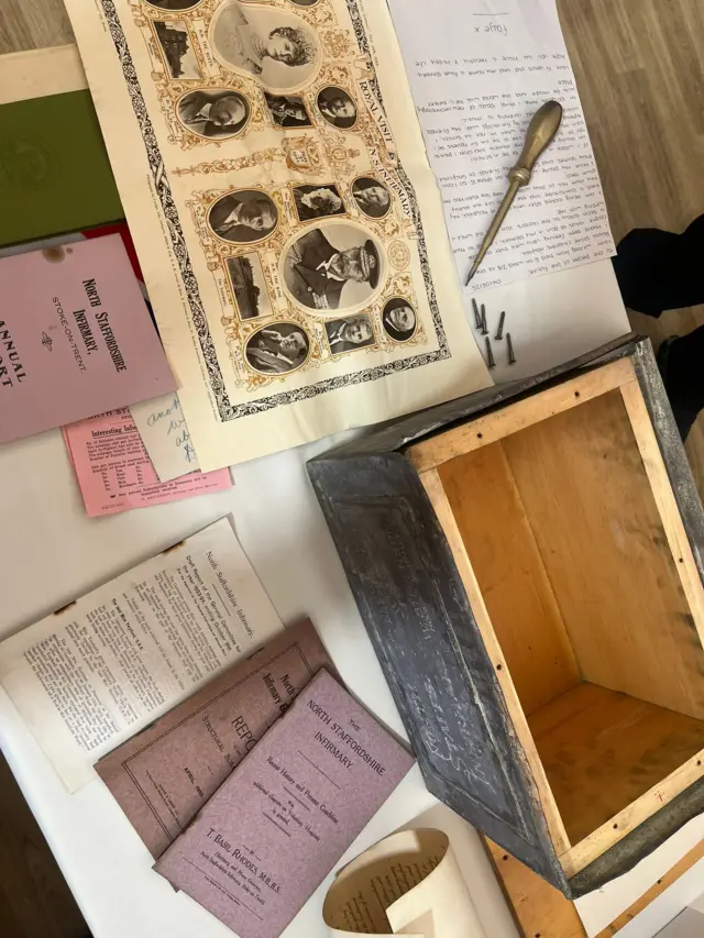 An open box surrounded by a number of documents, one of which has portrait pictures of people.