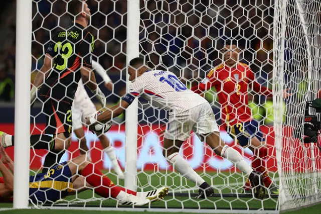 Kylian Mbappe grabs the ball from the back of the net