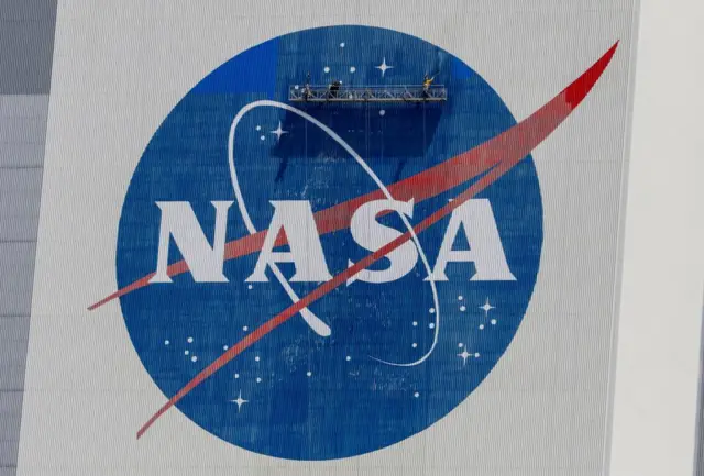 Workers pressure-wash the logo of NASA on the Vehicle Assembly Building before SpaceX will send two NASA astronauts to the International Space Station aboard its Falcon 9 rocket, at the Kennedy Space Center in Cape Canaveral, Florida, U.S., May 19, 2020
