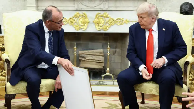 Friedrich Merz presents the framed birth certificate of  Trump's grandfather