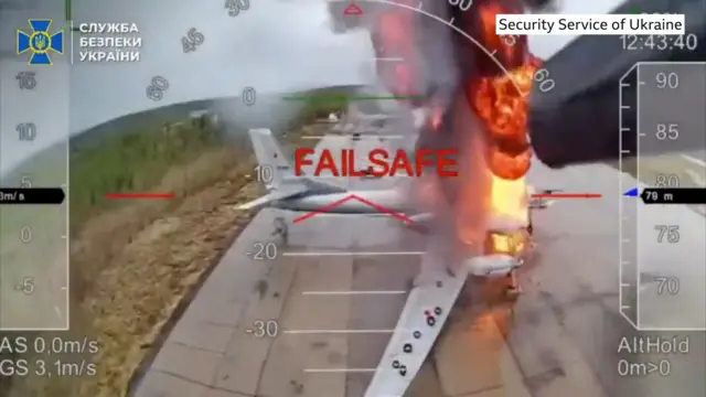 A Russian aircraft is seen on fire and the word, failsafe, appears on the screen. It appears to be taken from the vantage point of a drone.