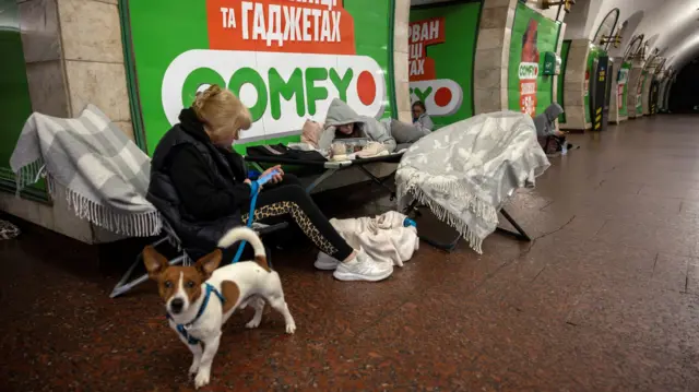 woman holds her dog on a leash at a metro station in Kyiv