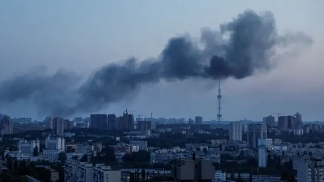 Aerial shot of Kyiv at dawn, with grey smoke floating over the city