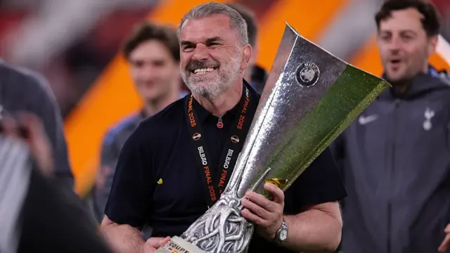 Ange Postecoglou, head coach of Tottenham Hotspur, celebrates with the trophy