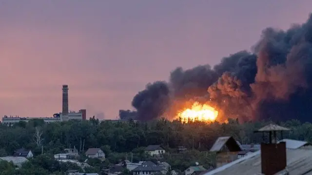 Fire is seen among the smoke clouds billowing from a Russian attack on Kharkiv