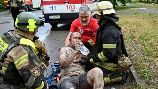 An injured person drinks water after rescuers carried him out of ruins of
