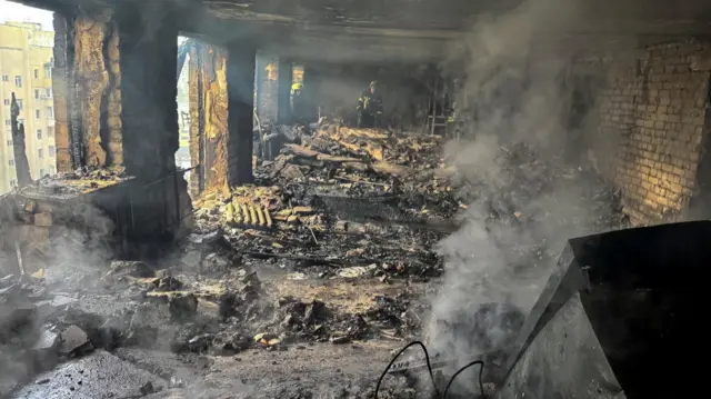 Firefighters work inside an apartment building hit by a Russian drone strike