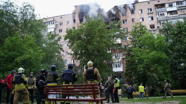 Rescue workers look at smouldering building in Kharkiv