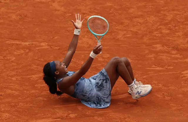 Coco Gauff sits on the clay court