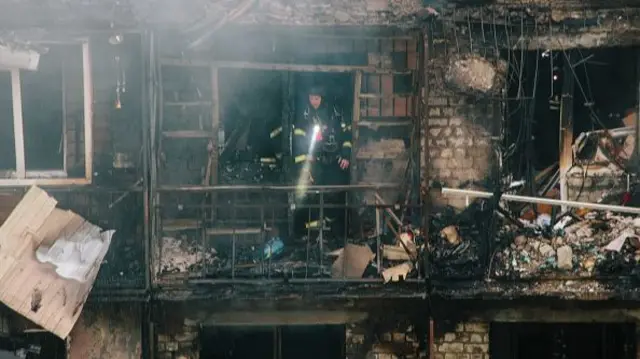 A firefighter inspects the burned-out apartments in Kharkiv