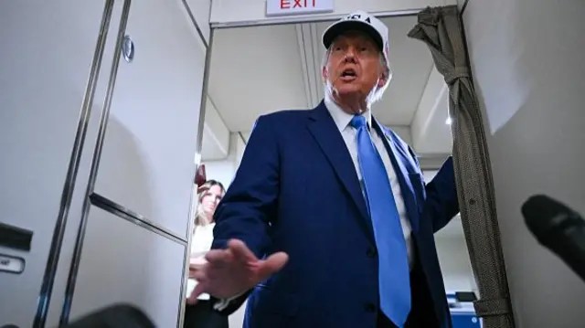 US President Donald Trump talks to the press aboard Air Force One