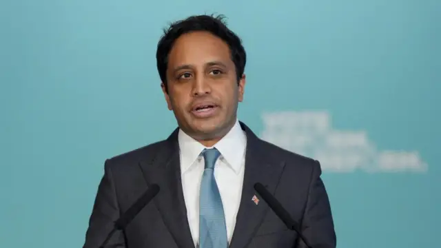 Zia Yusuf speaking into microphone, wearing a suit.