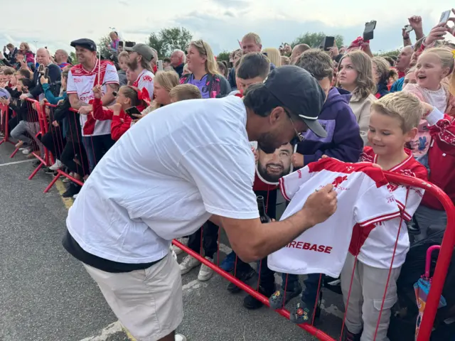 A Hull KR player signs a shirt for a fan