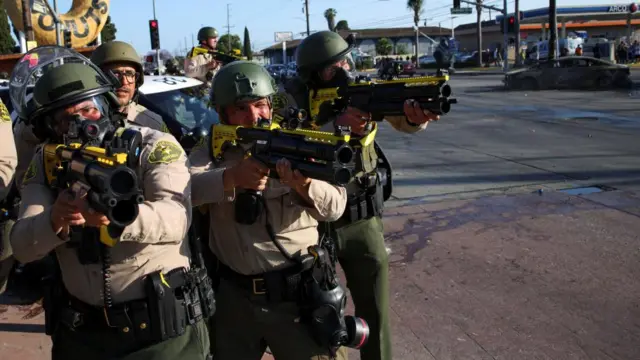 ICE officers seen in helmets outside a branch of a donut store