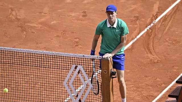 Jannik Sinner holds the net post