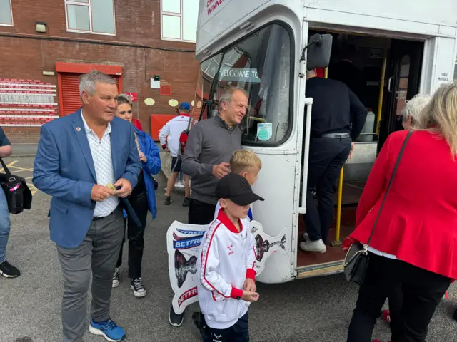 A group of people walk towards a white bus which will take Hull Kingston Rovers players and the Challenge Cup on a victory parade