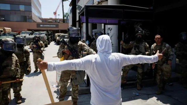 A demonstrator extends their arms during a protest against federal immigration sweeps, as members of the California National Guard stand outside the Edward R. Roybal federal building after their deployment by U.S. President Donald Trump, in response to protests, in Los Angeles, California, U.S. June 8, 2025