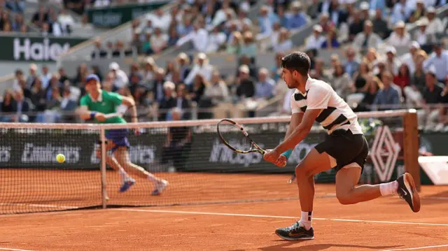 Carlos Alcaraz runs for a backhand at the net