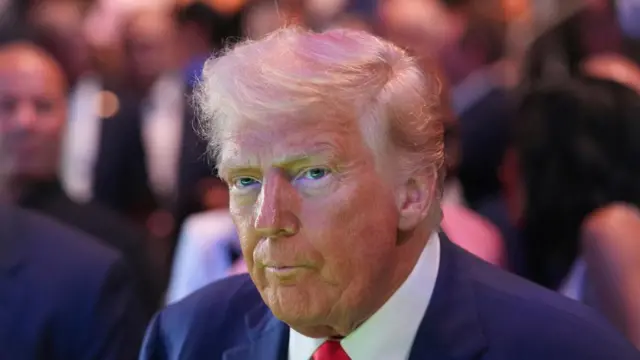 A file photo of Donald Trump - he is wearing a suit and his normal red tie, with a crowd behind him