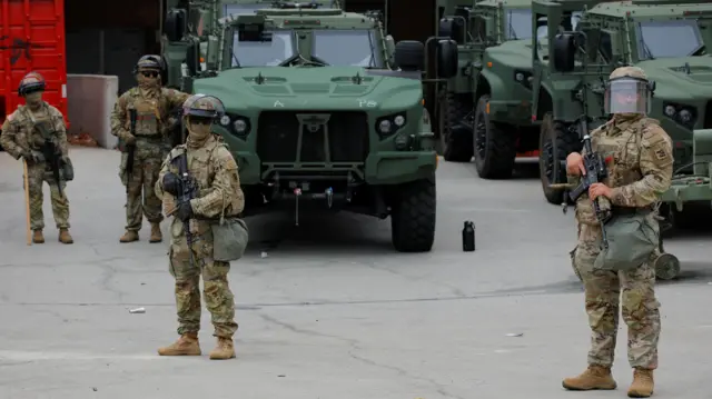 National Guard officials stand with vehicles