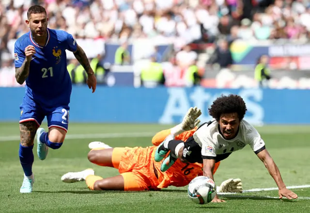 Lucas Hernandez, France's goalkeeper Mike Maignan and Germany's forward Karim Adeyemi vie for the ball