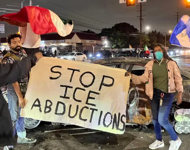 A photo showing Kuali Linda Aleman and a man holding a banner which says "Stop ICE abductions"