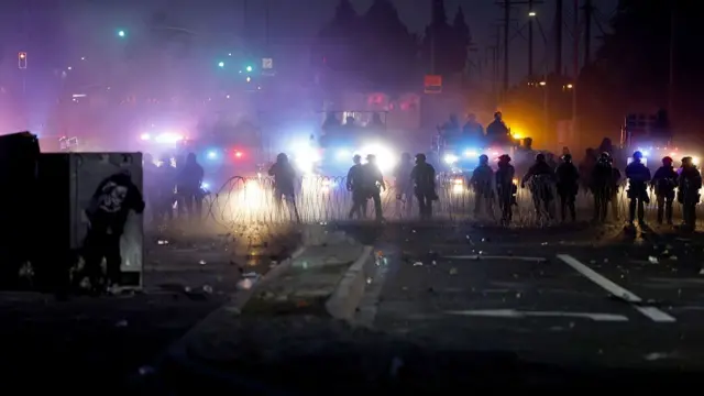 Law enforcement officers seen in a line at a makeshift barrier on a road in Los Angeles