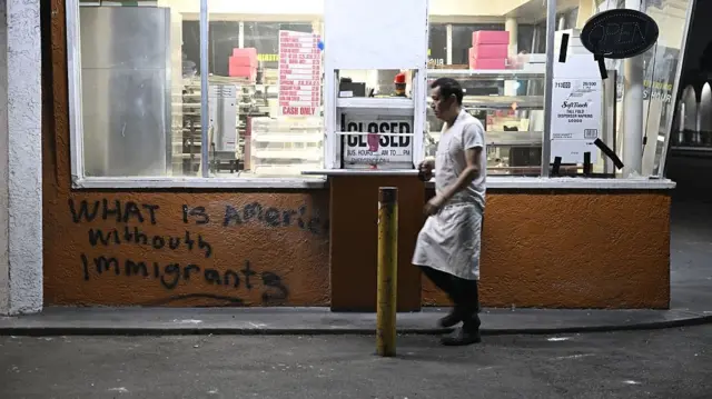A man walks in front of a vandalised shop in LA