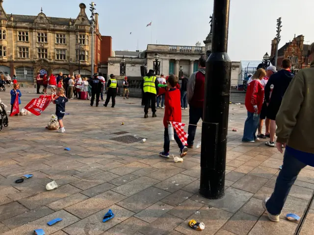 A crowd of people make their way out of Queen Victoria Square, Hull leaving behind cans and cups.