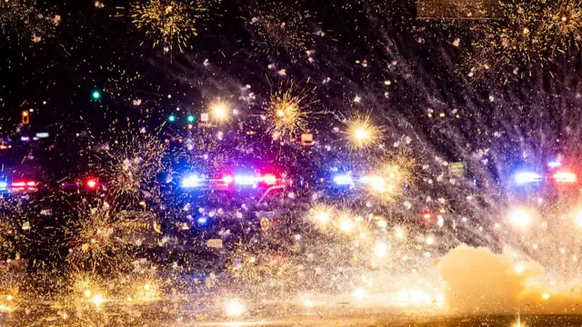 Fireworks explode in front of police cars in the Compton neighbourhood of LA