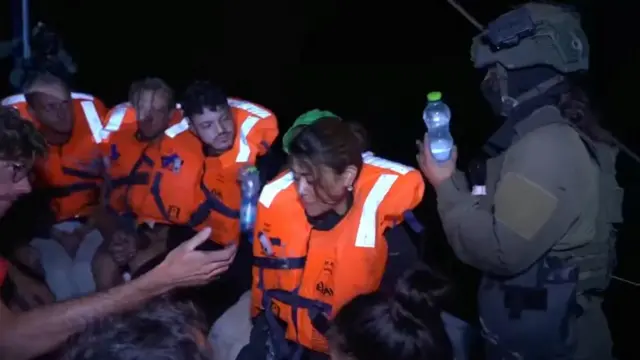 An Israeli solider passes water to those onboard the Gaza-bound British-flagged yacht "Madleen" after Israeli forces boarded the charity vessel as it attempted to reach Gaza