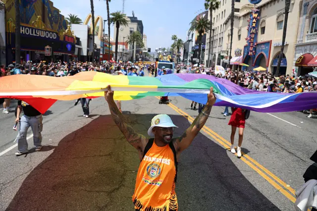 People hold up a rainbow flag for the LA Pride parade in Hollywood