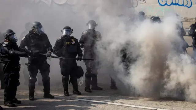 California Highway Patrol (CHP) officers stand in a cloud of tear gas during a protest against federal immigration sweeps, in downtown Los Angeles, California