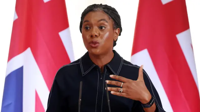 Kemi Badenoch gestures as she speaks in front of two union flags