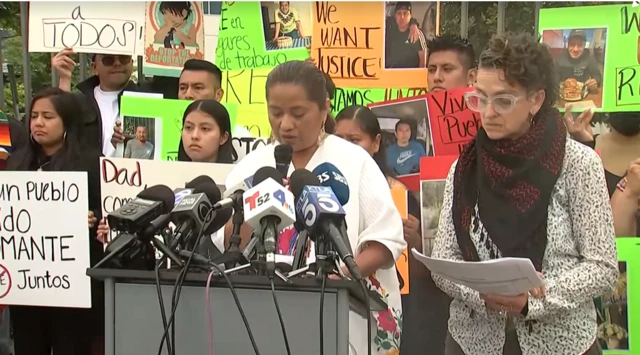 Dozens of people hold protest signs in a news conference