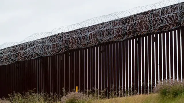 The US-Mexico border is seen with a border wall that has wire on top