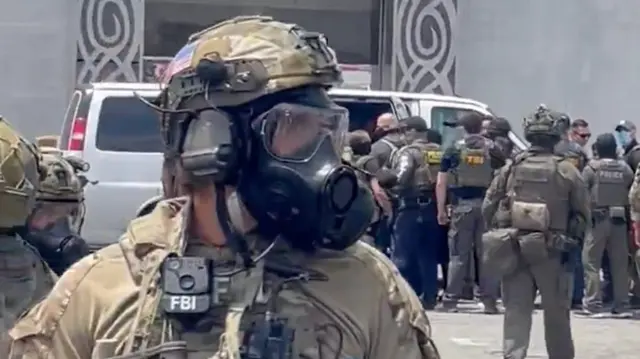 Law enforcement officials are seen wearing gas masks outside a federal building in Los Angeles