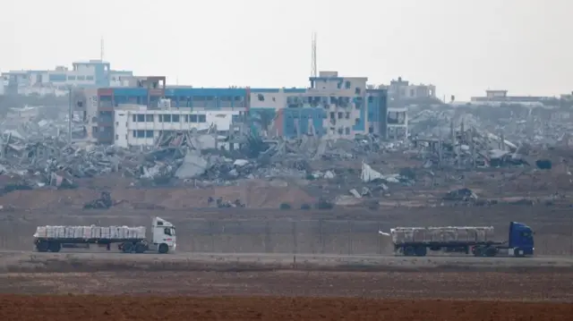 Trucks loaded with aid drive on the Israel-Gaza border as they make their way into Gaza, as seen from Israel, on 7 June