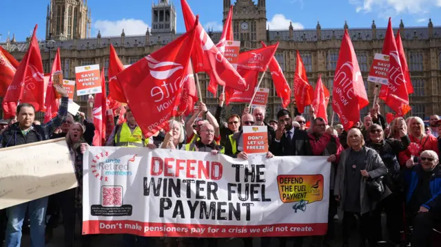 Campaigners holding up a sign which reads: Defend the winter fuel payment