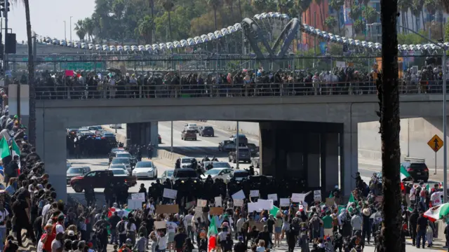 Demonstrators line a motorway slip road and bridge, blocking the passage for cars.
