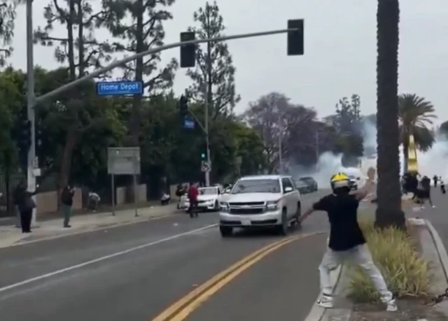 A video shows people running along Home Depot street, cars are speeding by.