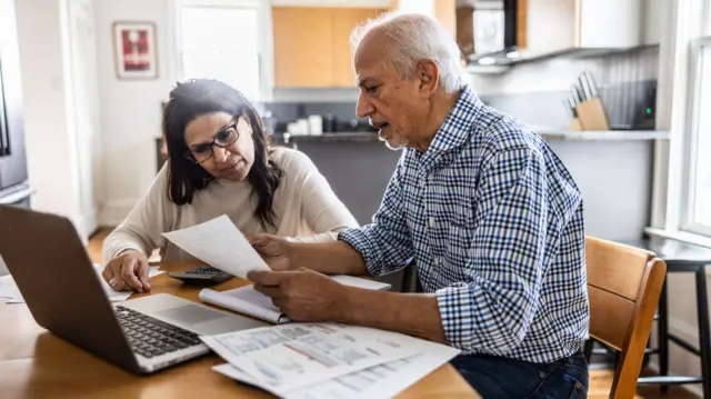 An older man and woman review documents in front of an iPad