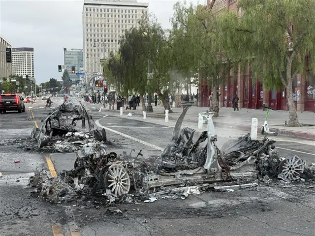 A burnt out car lies smoking after it was set on fire