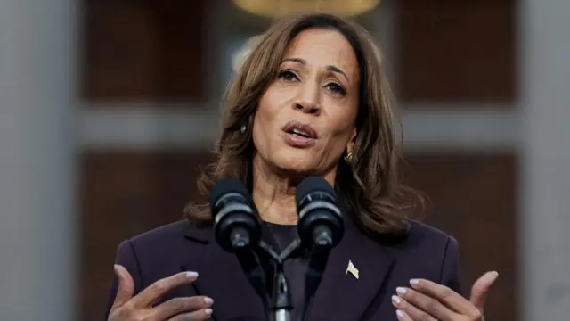 Kamala Harris speaks from a podium, wearing a dark suit.
